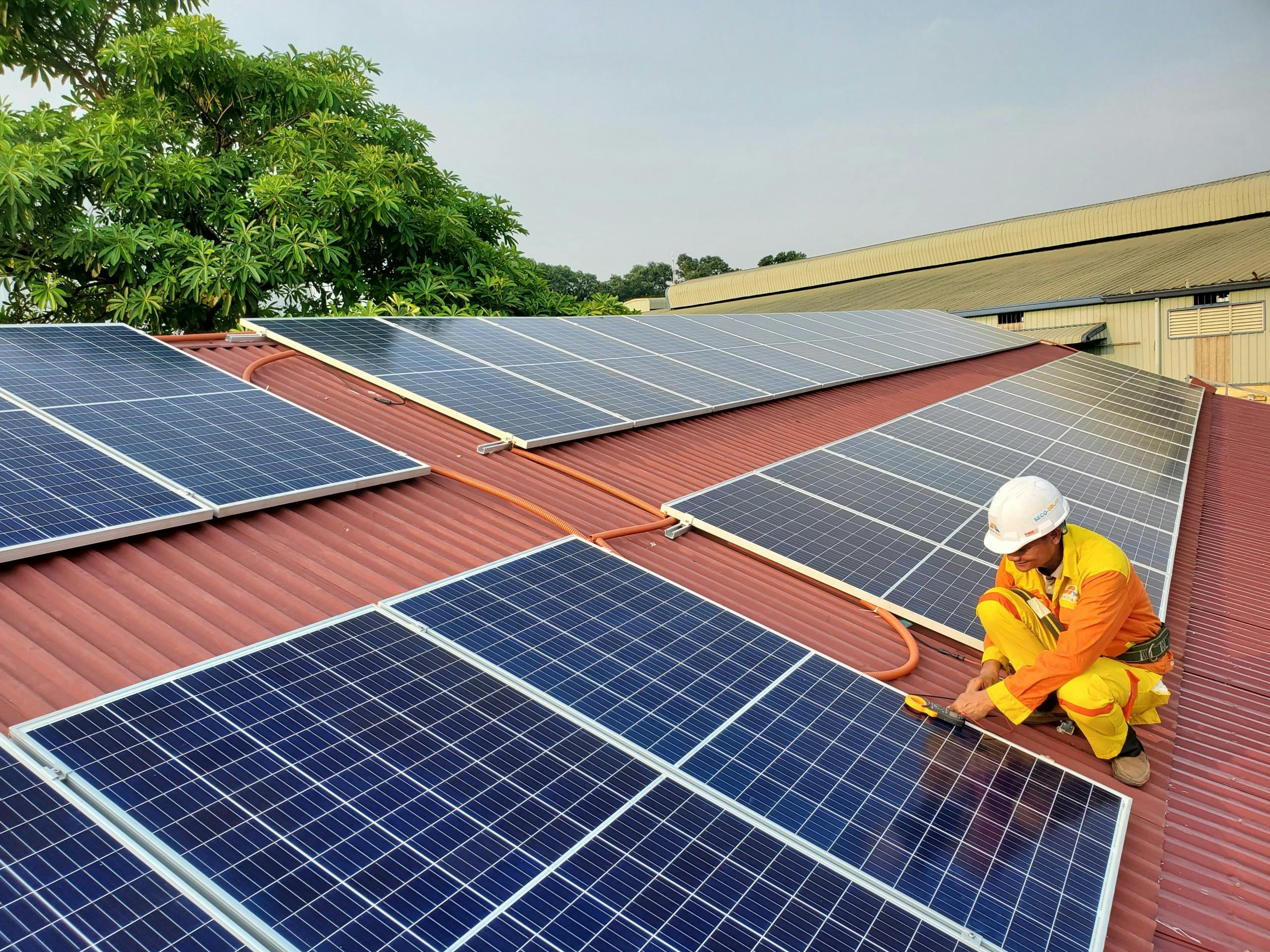 man wearing protective gear installing solar panels on a roof